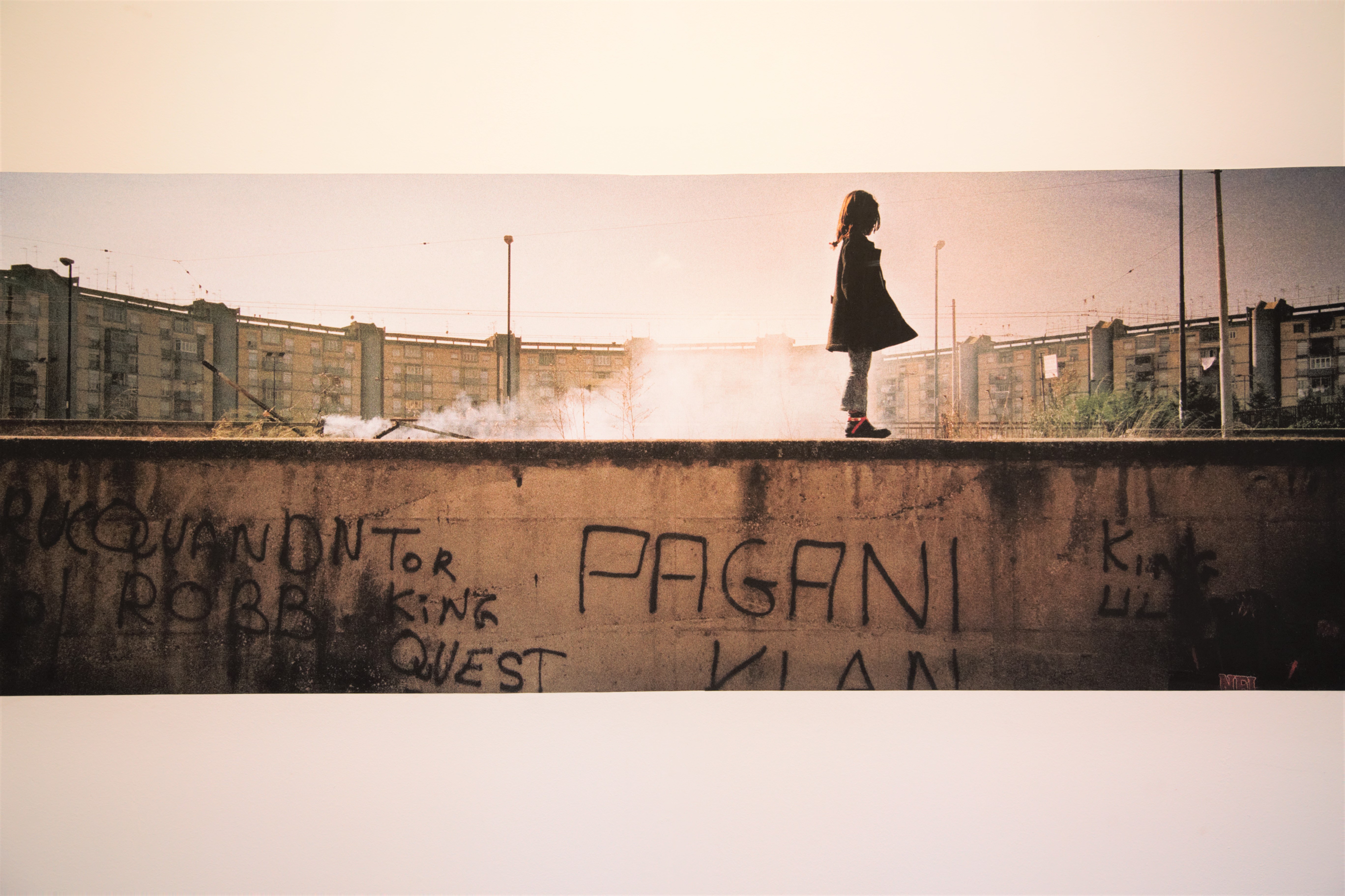 Una bambina cammina sopra a un muro