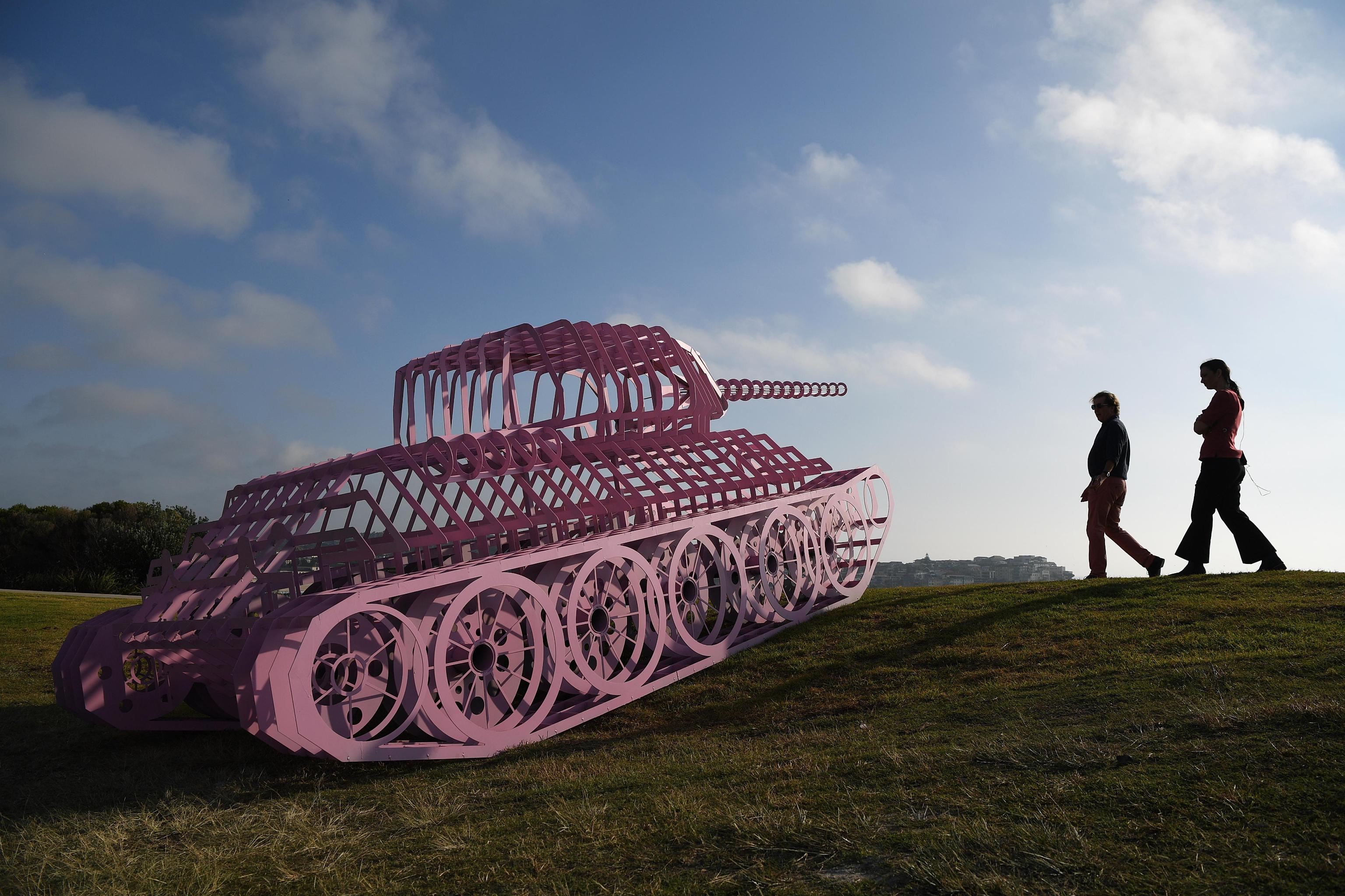 Persone camminano vicino alla scultura "Pink Tank Wrecked dell'artista ceco David Cerny
