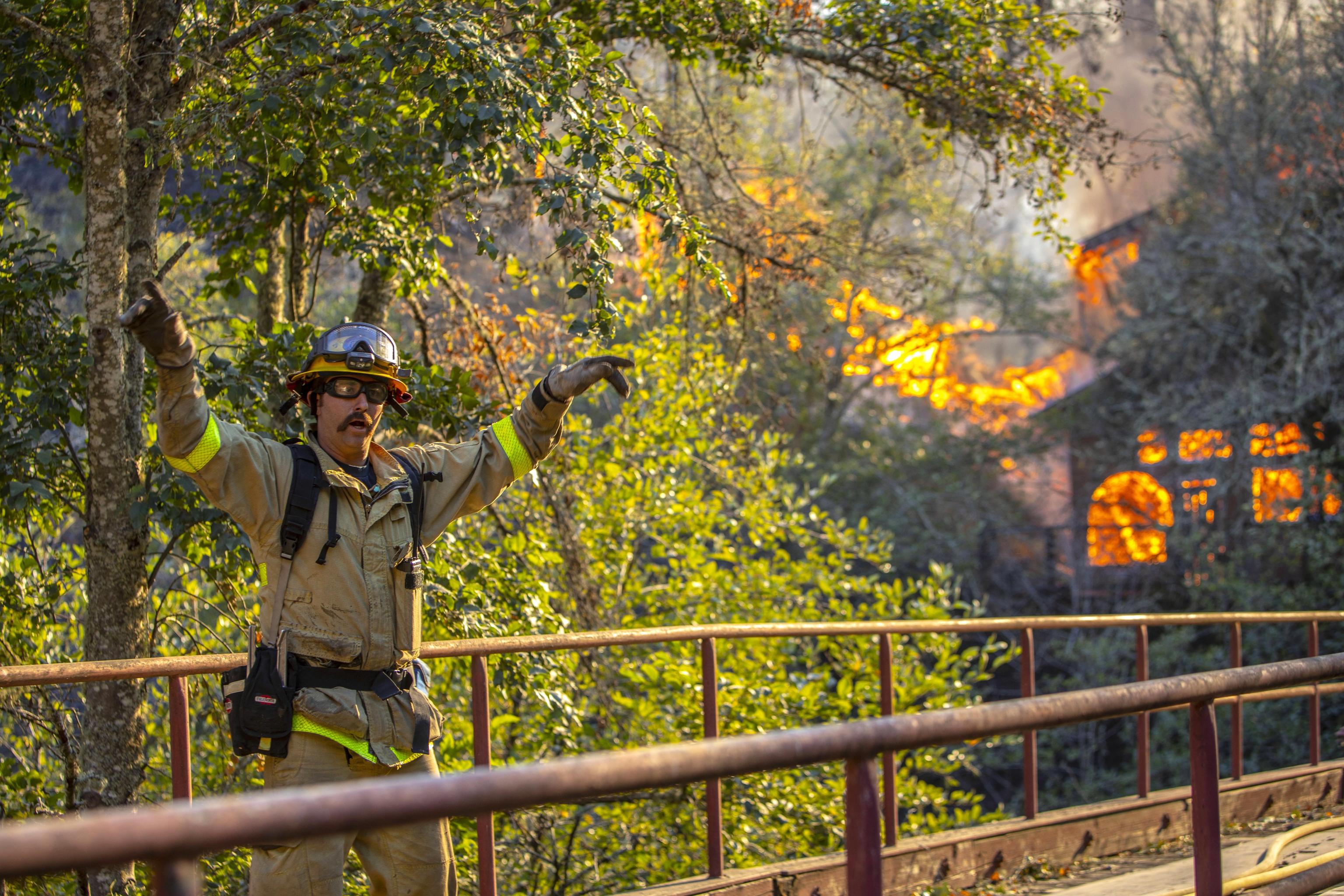 Un vigile del fuoco indica la strategia per domare le fiamme del rogo
