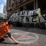 A Sydney un'attivista disegna il simbolo di Extinction Rebellion