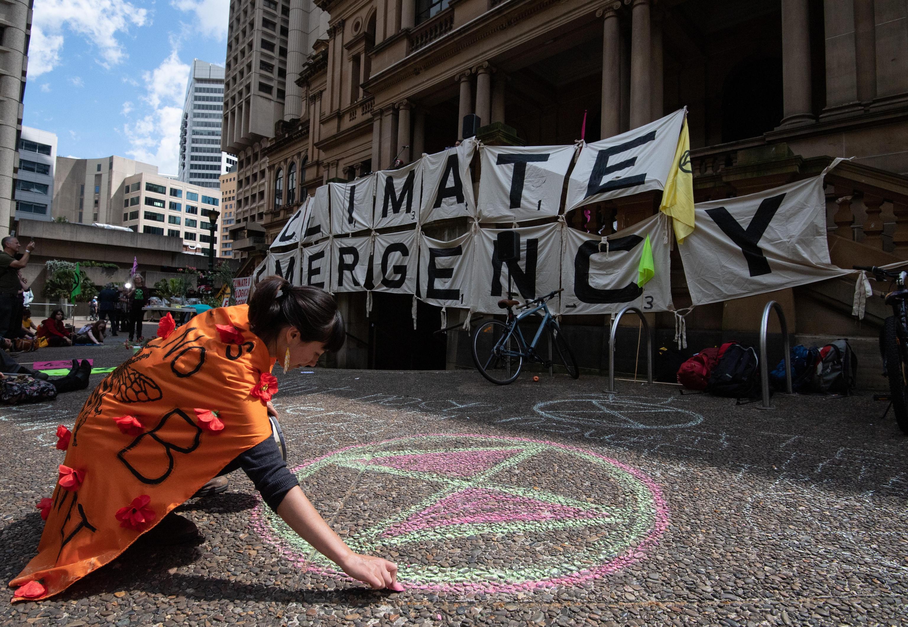 A Sydney un'attivista disegna il simbolo di Extinction Rebellion A Sydney un'attivista disegna il simbolo di Extinction Rebellion