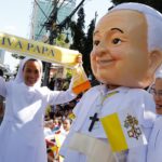 Un thailandese vestito con un costume di Papa Francesco sfila con delle suore con in mano una sciarpa che lo saluta