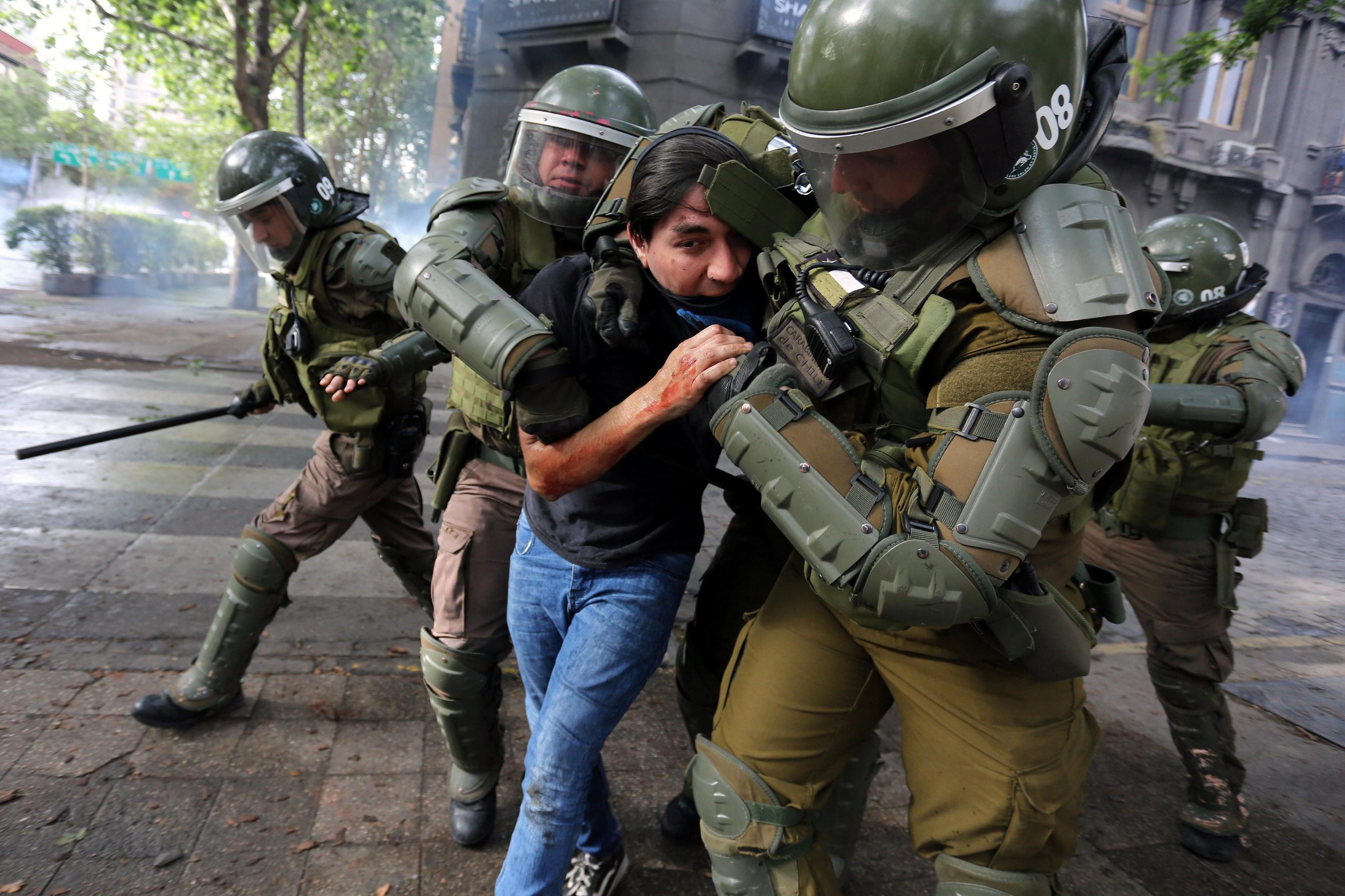 Un ragazzo viene portato via dalle forze dell'ordine durante le proteste