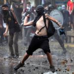 Un ragazzo lancia una pietra contro le forze dell'ordine
