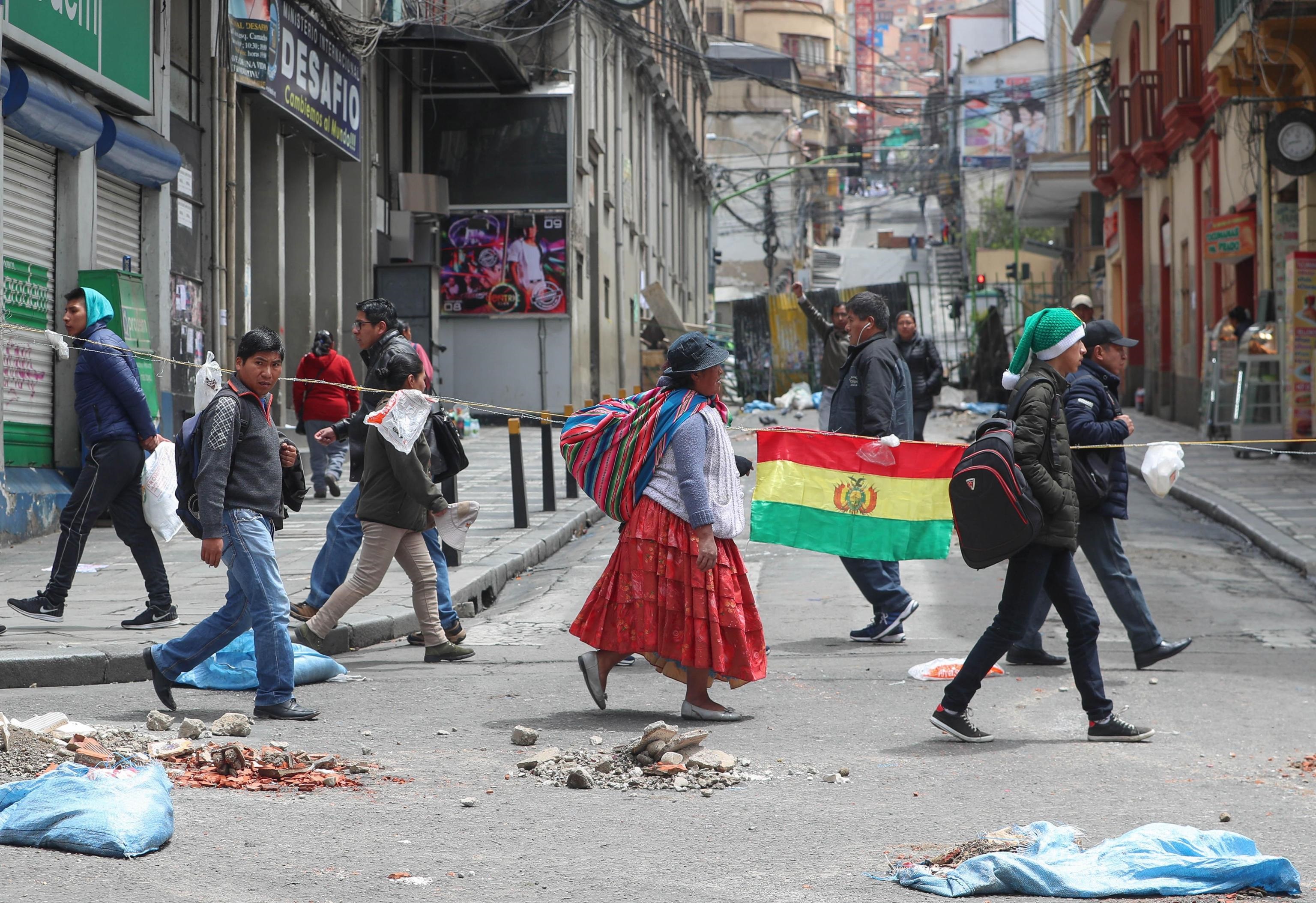 Cittadini boliviani si dirigono a Murillo Square, a La Paz. A terra numerosi detriti dovuti alle recenti proteste che hanno portato alle dimissioni e al trasferimento in Messico dell'ex Presidente Evo Morales. In queste ore la polizia boliviana sta assumendo il controllo delle strade delle principali città del Paese