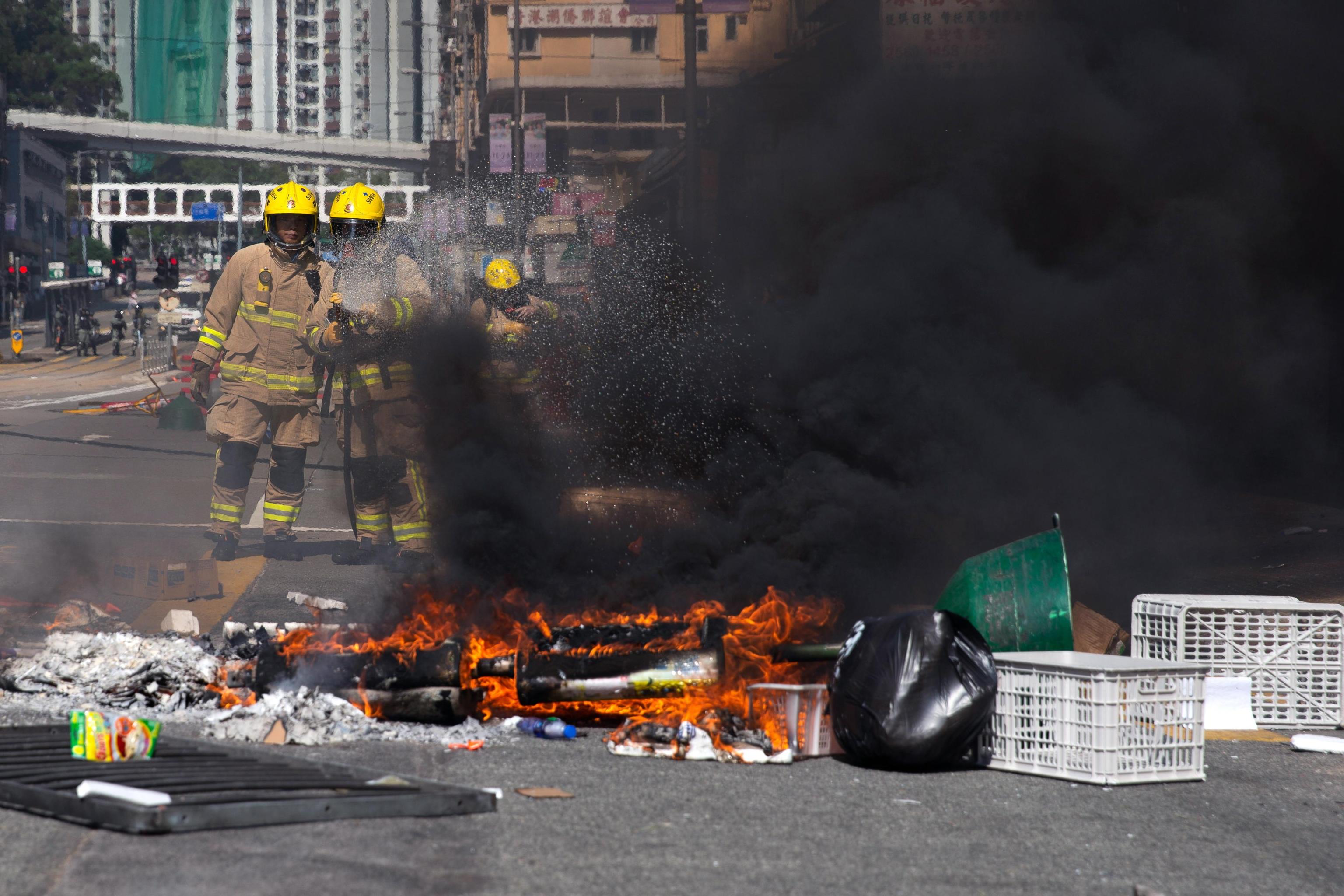 La protesta di Hong Kong infiamma tutta la città. Due pompieri alle prese con le barricate date fuoco dai manifestanti La protesta di Hong Kong infiamma tutta la città. Due pompieri alle prese con le barricate date fuoco dai manifestanti