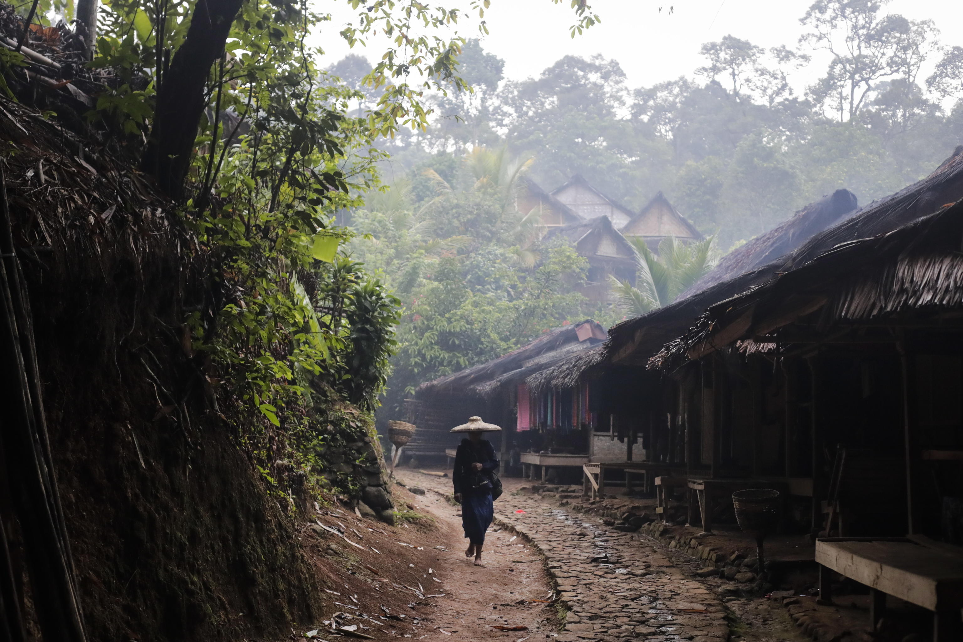 Un membro della tribù cammina tra le abitazioni del villaggio Kanekes