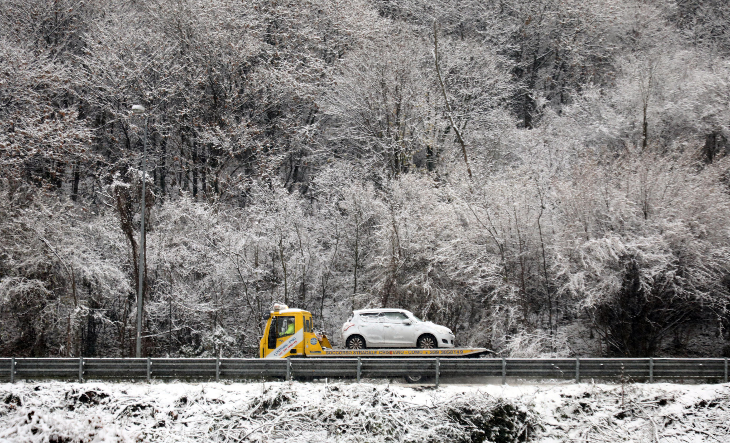 A Milano c'è l'allerta meteo. Alle porte di Como ha nevicato. Un carro attrezzi porta via una macchina