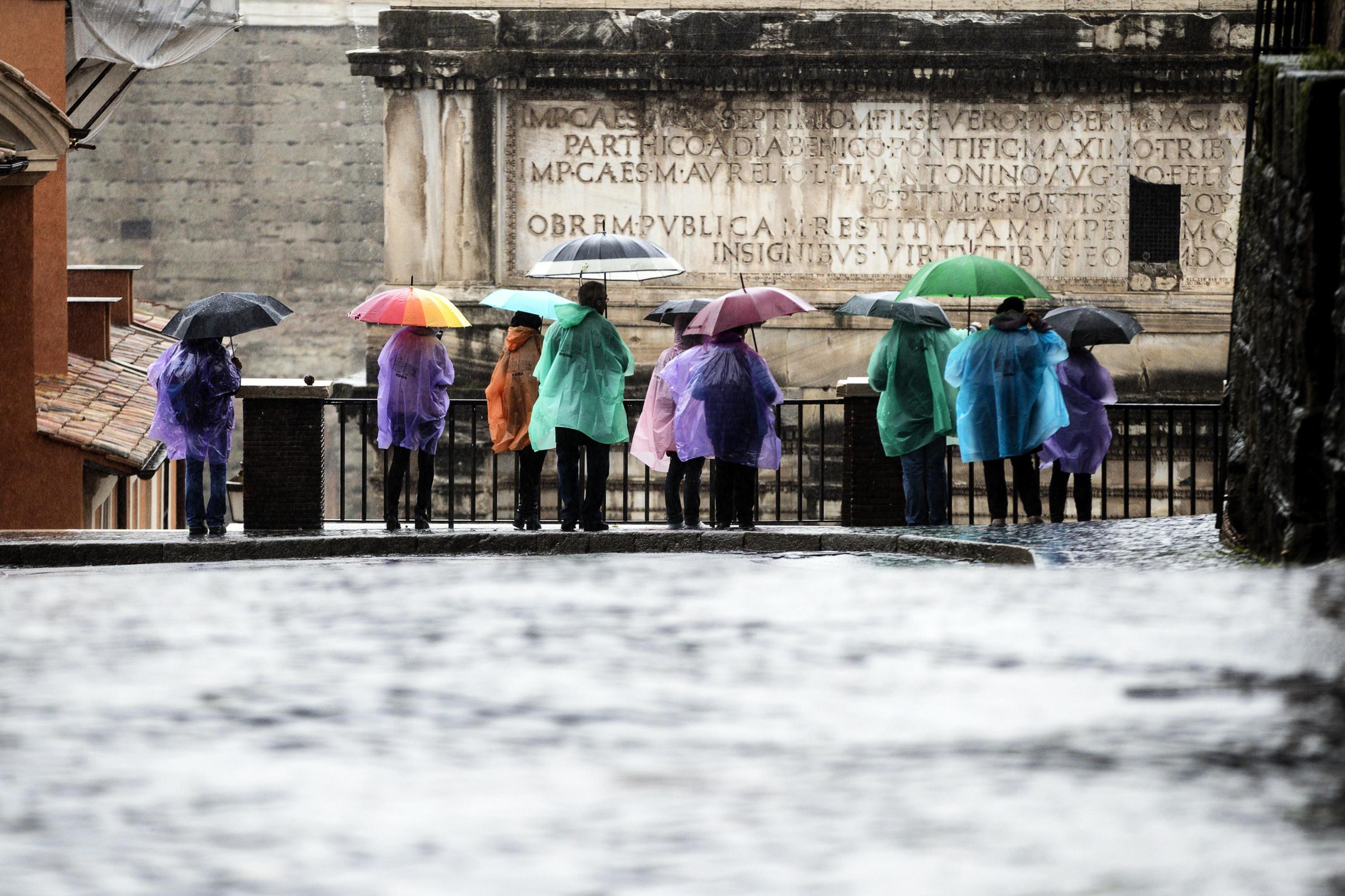 Allerta meteo anche a Roma. Alcuni turisti si riparano dalla pioggia in Campidoglio