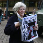 Ann Widdecombe con un giornale davanti alla stazione ferroviaria