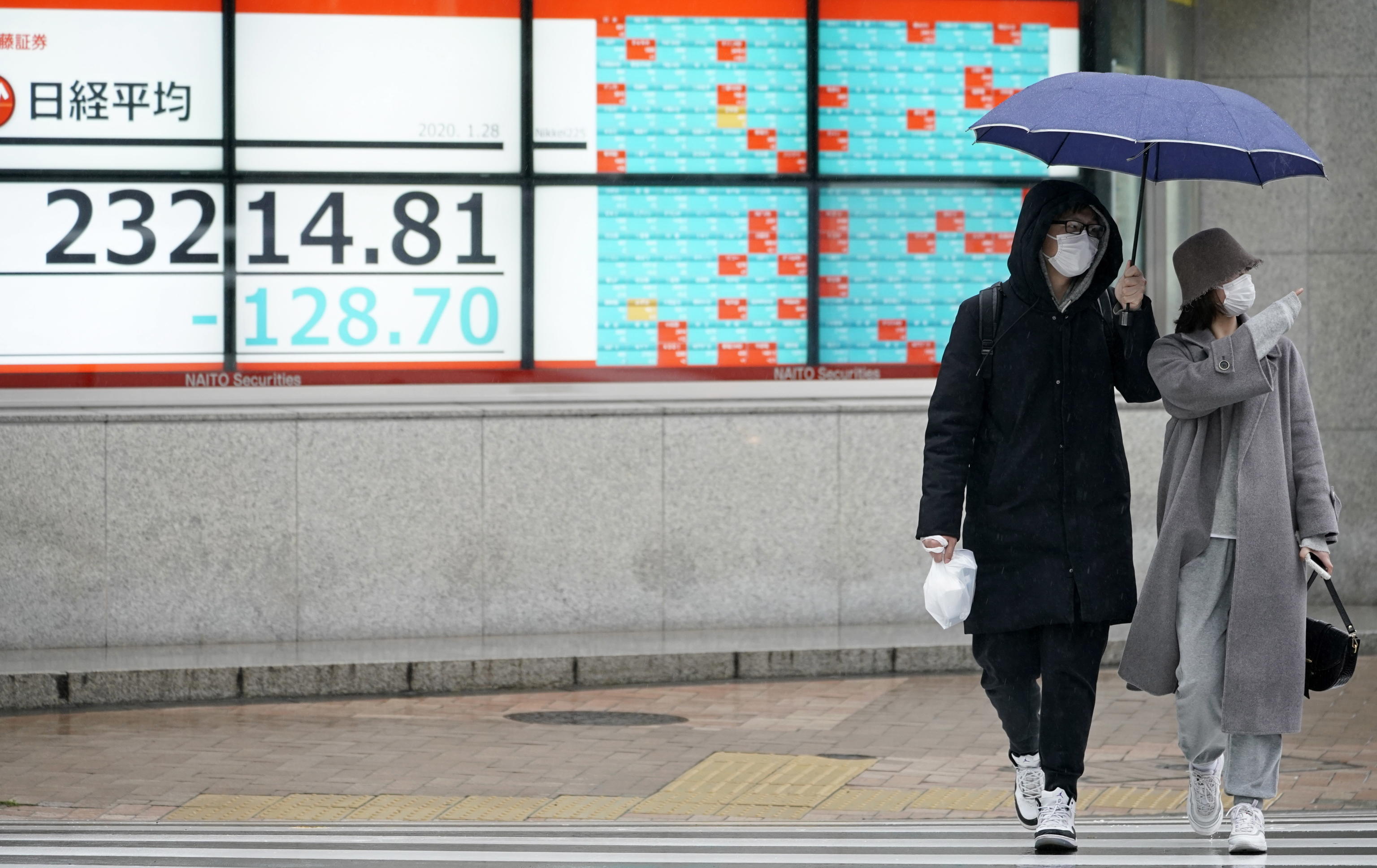 Una coppia di giapponesi che passeggia per Tokyo con le maschere antivirus