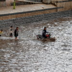 Le famiglie non si arrendono alla forza dell'acqua e tentano di attraversare gli immensi corsi d'acqua anche a bordo di motociclette