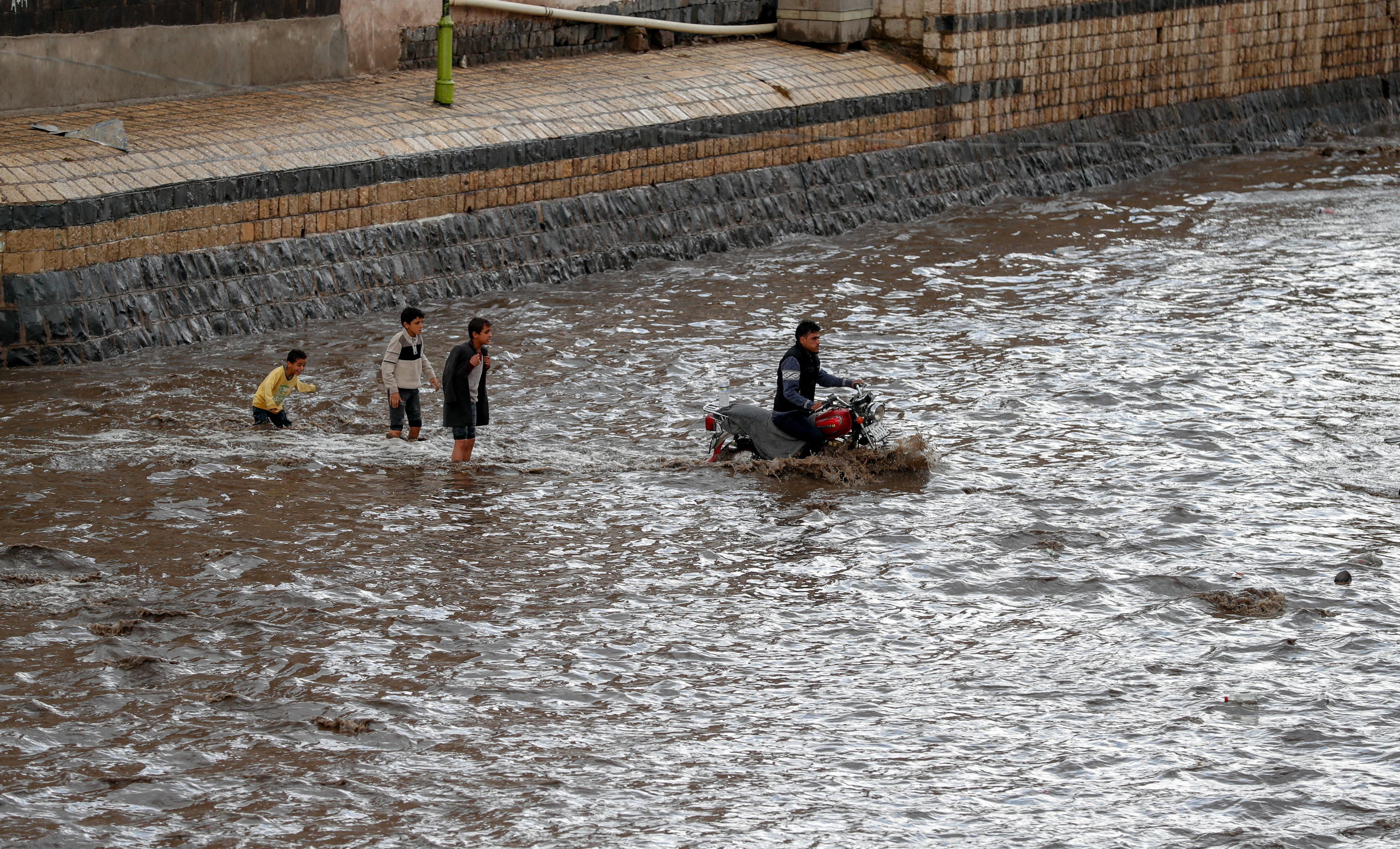 Le famiglie non si arrendono alla forza dell'acqua e tentano di attraversare gli immensi corsi d'acqua anche a bordo di motociclette