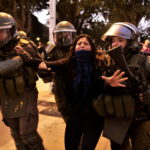 La polizia intervene per fermare le proteste e blocca una manifestante La polizia intervene per fermare le proteste e blocca una manifestante