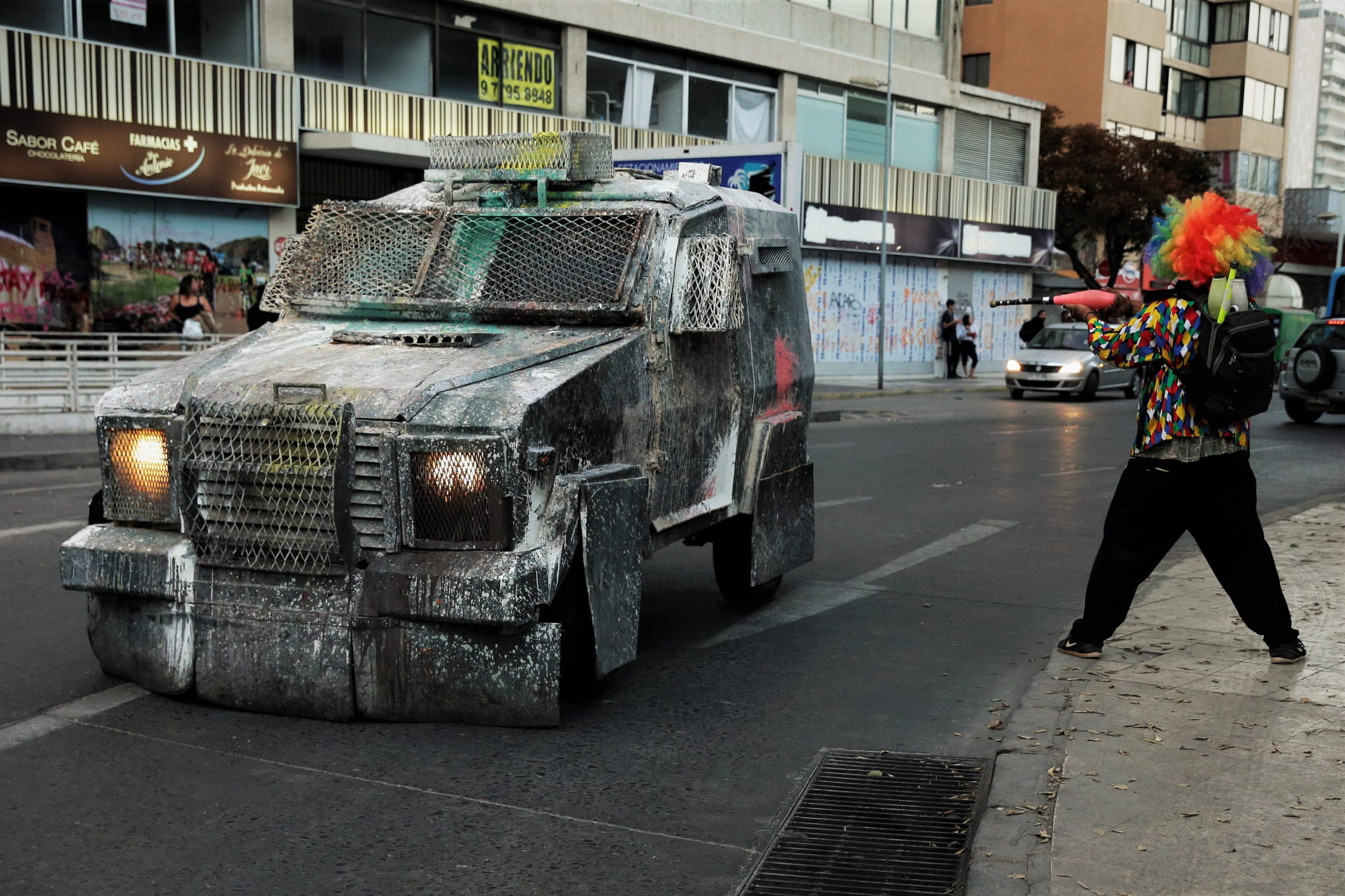 Un giocoliere da strada finge di sparare al blindato dei militari con una clava Un giocoliere da strada finge di sparare al blindato dei militari con una clava