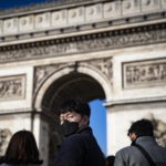 A Parigi i turisti sugli Champs Elysees indossano le tipiche mascherine