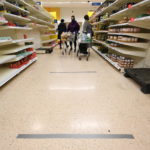 Fra le corsie di un supermercato londinese: per indicare la distanza di sicurezza sono stati applicati dei nastri adesivi sul pavimento