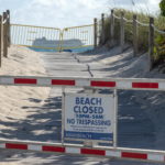 Un'altra spiaggia chiusa con la sbarra abbassata e una nave da crociera sullo sfondo Un'altra spiaggia chiusa con la sbarra abbassata e una nave da crociera sullo sfondo