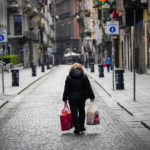 Una donna cammina con i sacchi della spesa nelle strade deserte di Napoli