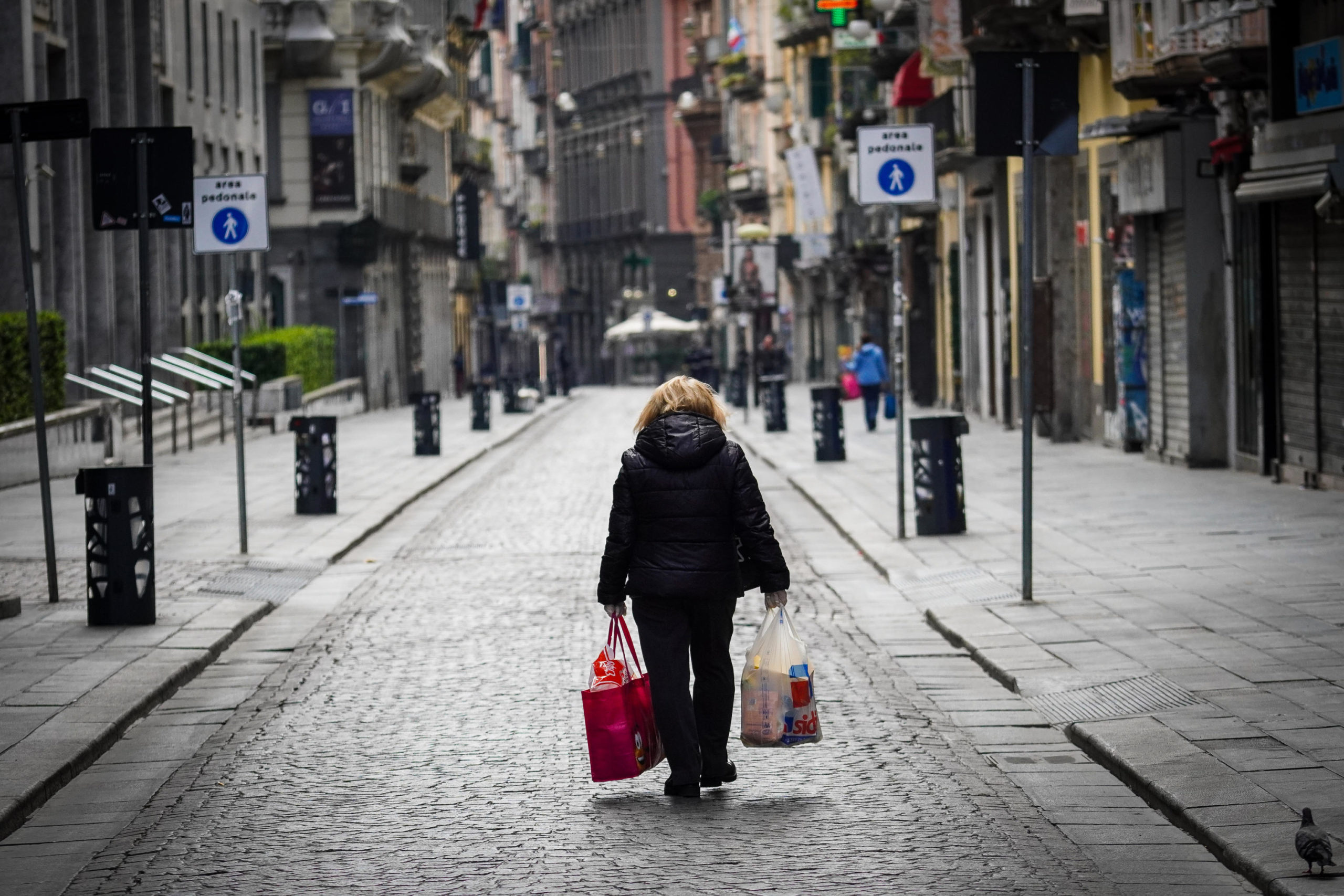 Una donna cammina con i sacchi della spesa nelle strade deserte di Napoli