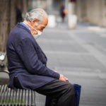 Un uomo con la mascherina seduto su una panchina a Napoli