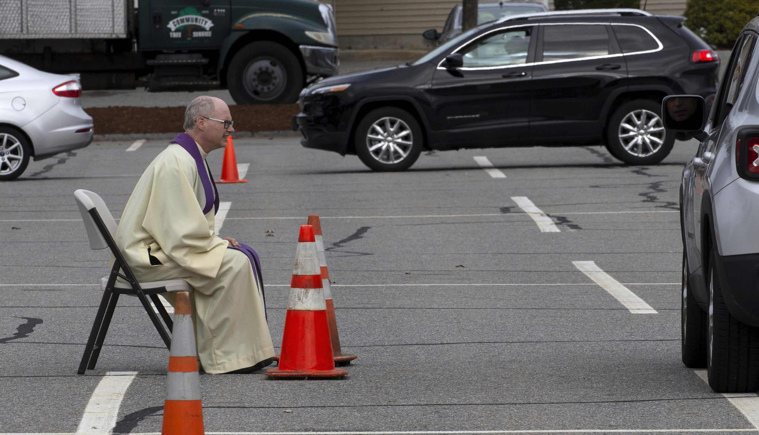 Padre Mahoney ascolta la confessione di un parrocchiano rispettando la distanza di sicurezza