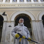 Panagiotis Mpakoulas, lavoratore municipale, spruzza disinfettante fuori da una chiesa nel centro di Atene