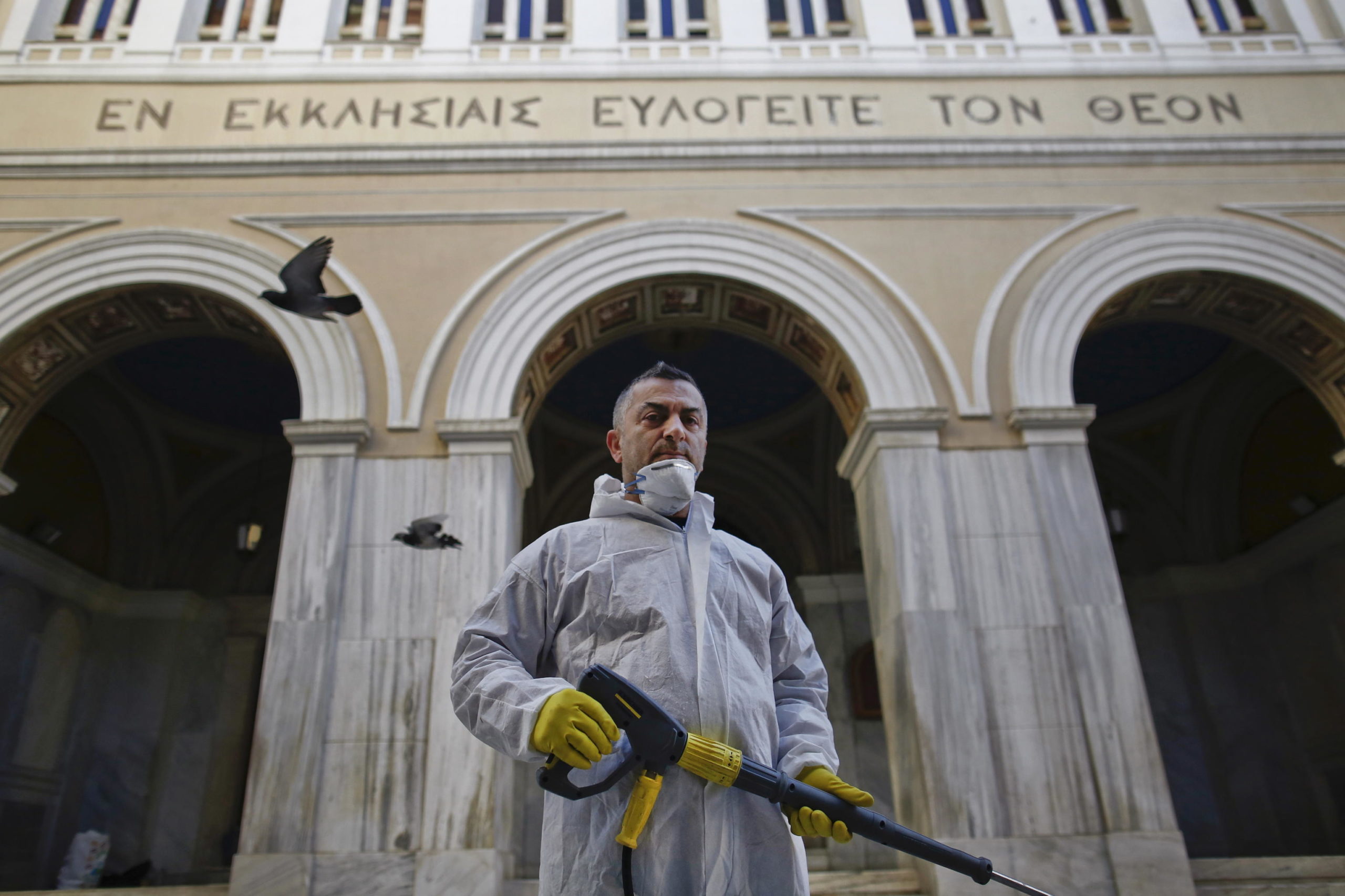 Panagiotis Mpakoulas, lavoratore municipale, spruzza disinfettante fuori da una chiesa nel centro di Atene