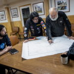 Tre scienziati dell'INACH si consultano con il pilota dell'elicottero sul percorso da seguire