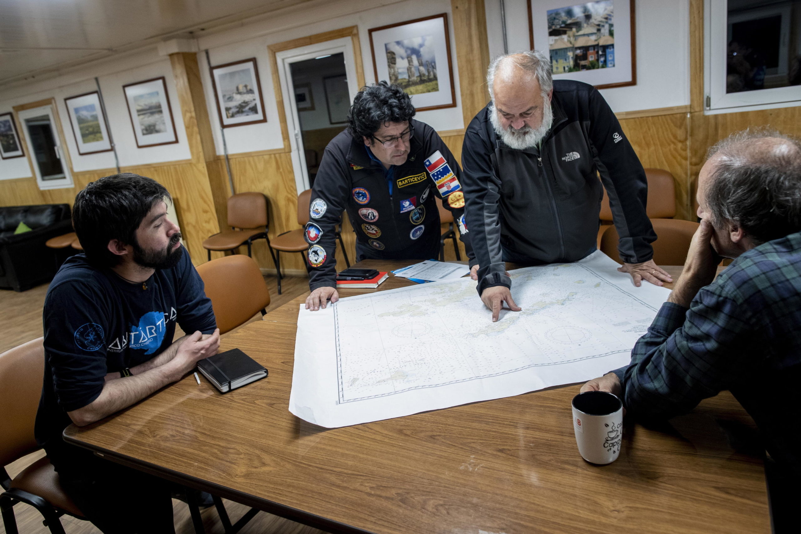 Tre scienziati dell'INACH si consultano con il pilota dell'elicottero sul percorso da seguire