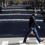 Un uomo con la mascherina attraversa la sesta strada a New York. Il governatore ha annunciato un ordine esecutivo che richiederà a tutti di indossarle fuori di casa