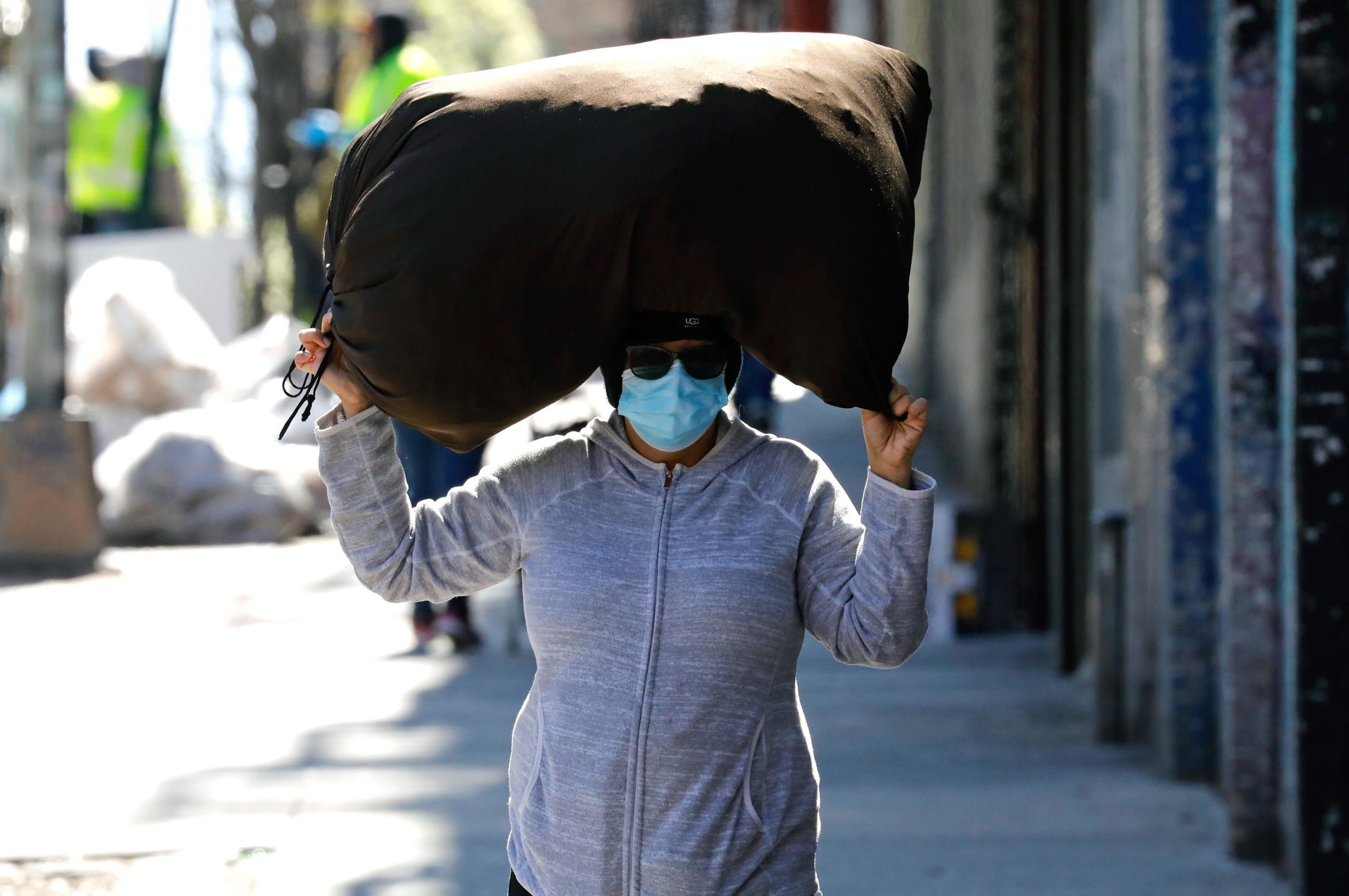 Una donna indossa una maschera protettiva mentre porta un sacco in testa nel Bronx