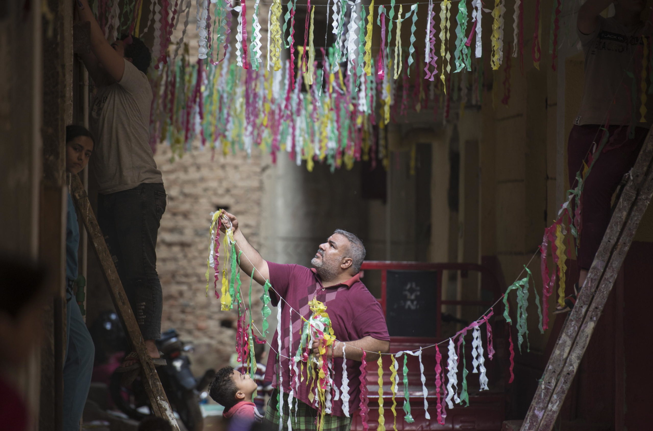 Per le strade di Giza, in Egitto, due uomini appendono ornamenti e decorazioni. Si tratta di una tradizione locale