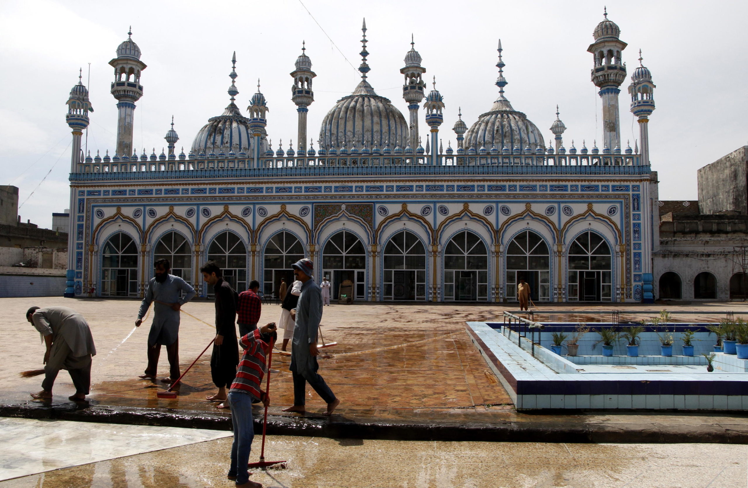 Alcuni uomini puliscono l’esterno della moschea di Rawalpindi, in Pakistan, in vista del mese sacro