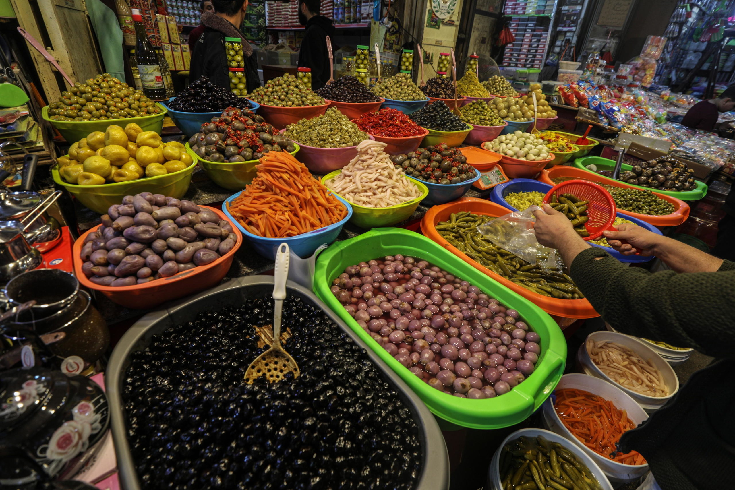 Un commerciante palestinese vende olive e cetrioli al mercato di Gaza Un commerciante palestinese vende olive e cetrioli al mercato di Gaza