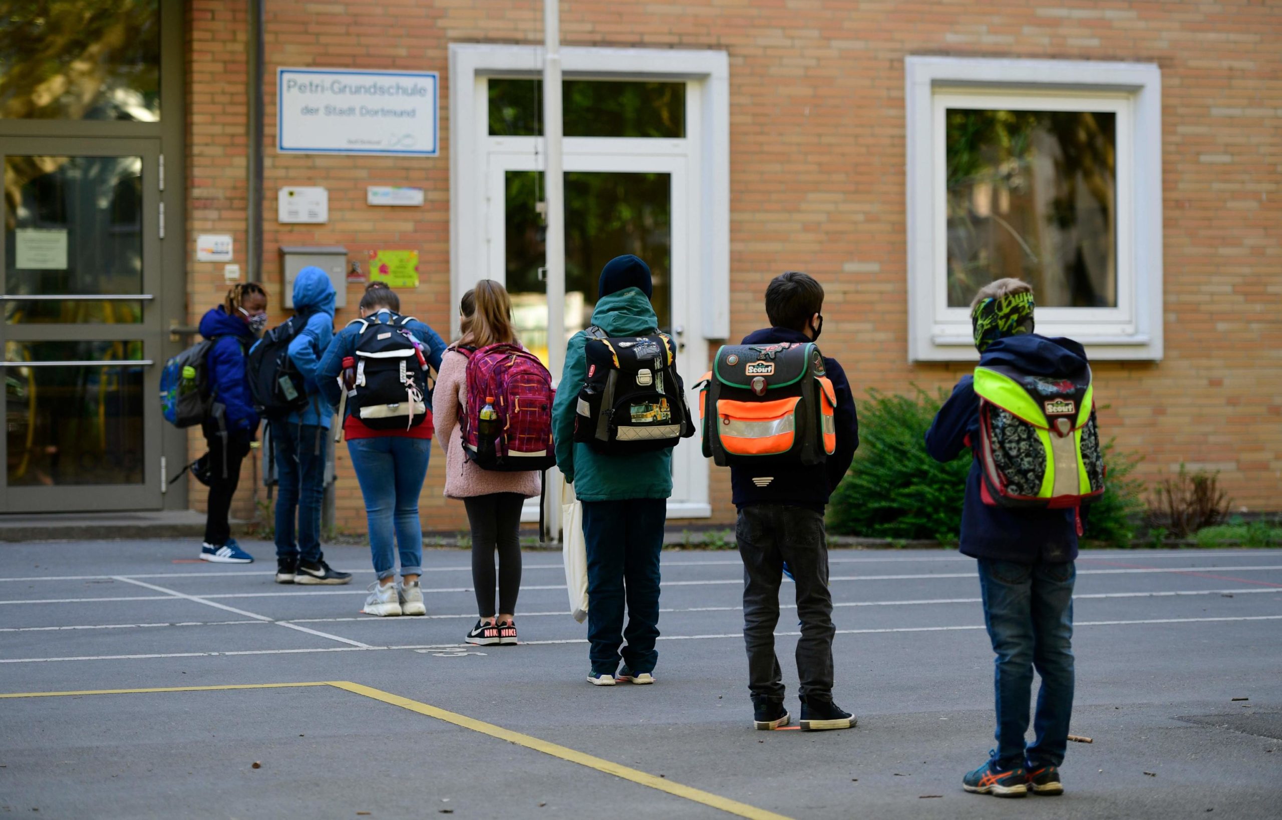 I bambini rispettano la distanza di sicurezza, mentre sono in fila davanti alla scuola primaria "Petri", nella Germania ovest