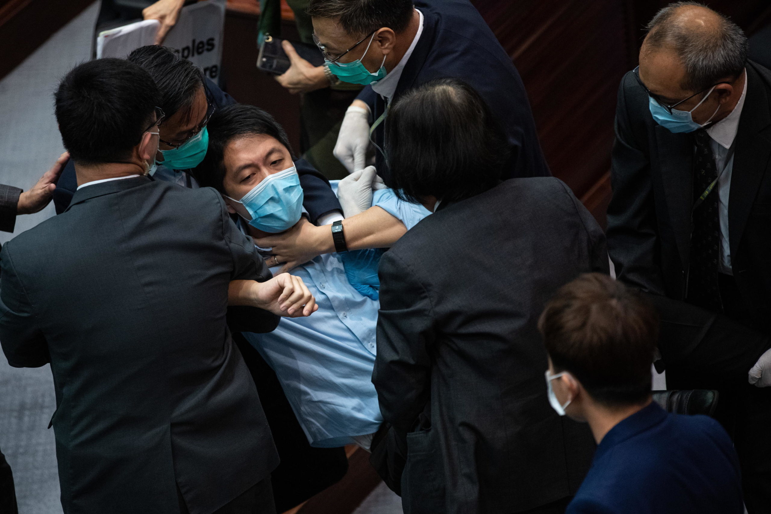 Il deputato pan-democratico Wu Chi-wai viene portato fuori dagli agenti di sicurezza