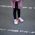 Una bambina sta in piedi sulla linea disegnata per rispettare la fila. Tutti gli alunni sono muniti di mascherine come da protocollo