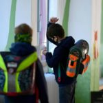 Un bambino si disinfetta le mani, in attesa di dirigersi in aula per le lezioni. Indossa la mascherina come tutti i suoi compagni