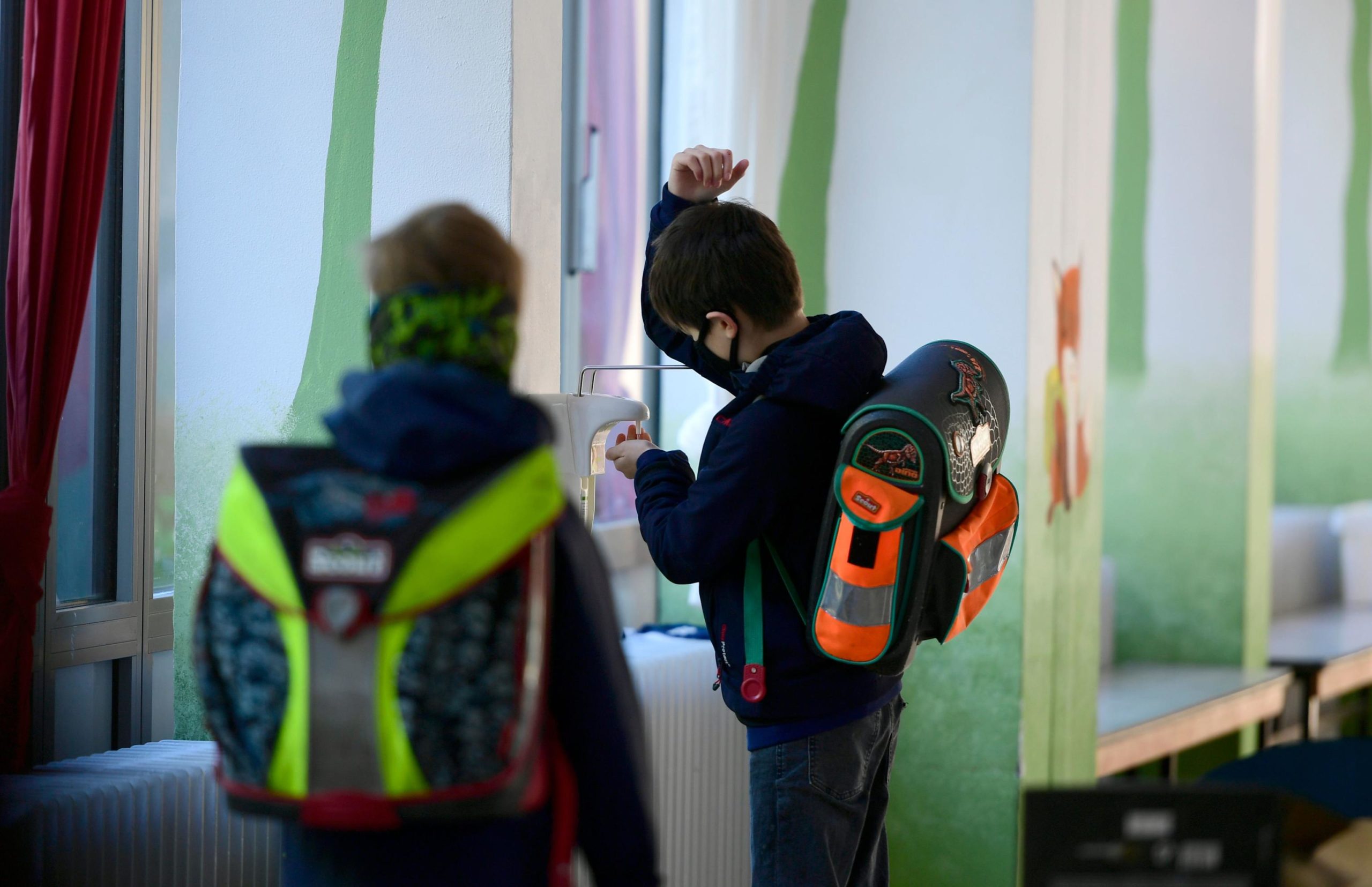 Un bambino si disinfetta le mani, in attesa di dirigersi in aula per le lezioni. Indossa la mascherina come tutti i suoi compagni
