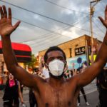 Un ragazzo protesta indossando la mascherina
