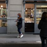 Una ragazza acquista un caffè da asporto in via Vincenzo Monti a Milano