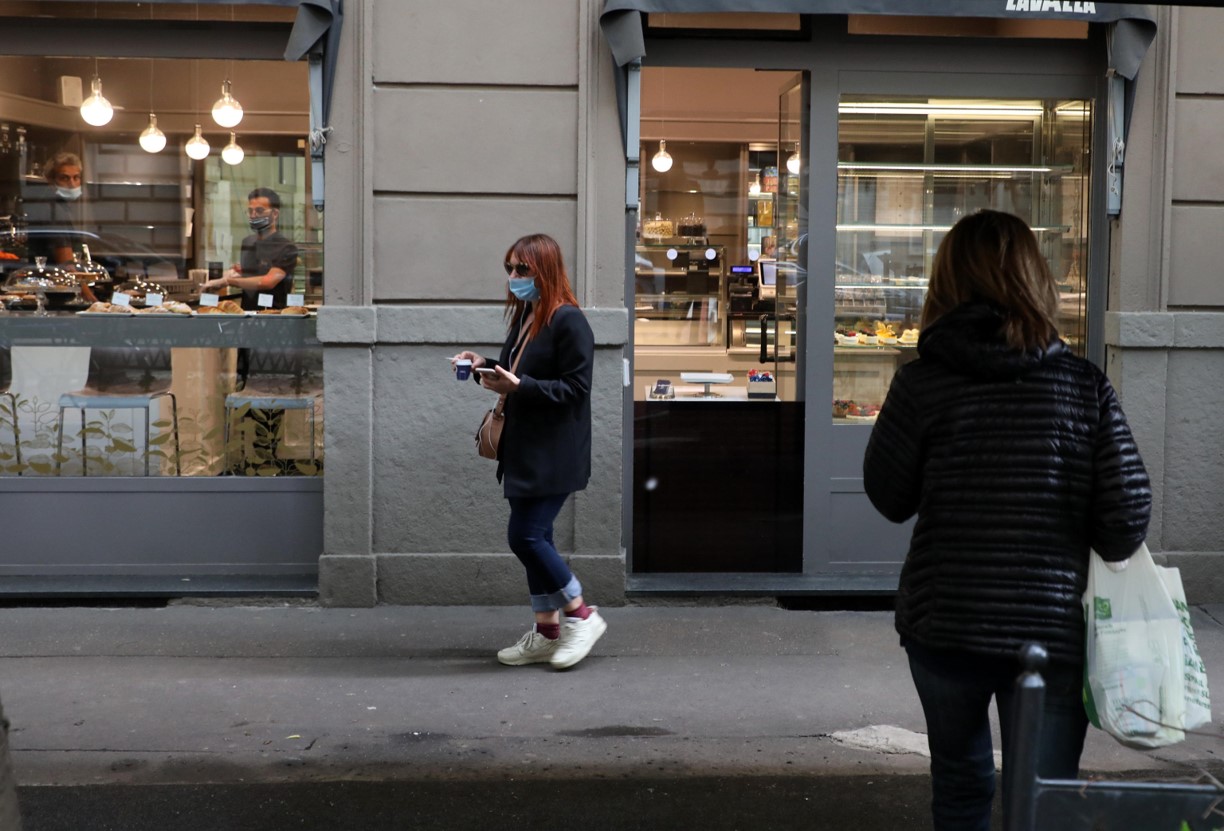 Una ragazza acquista un caffè da asporto in via Vincenzo Monti a Milano
