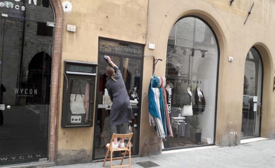 Una negoziante riapre la sua attività pulendo la vetrina nel centro di Perugia