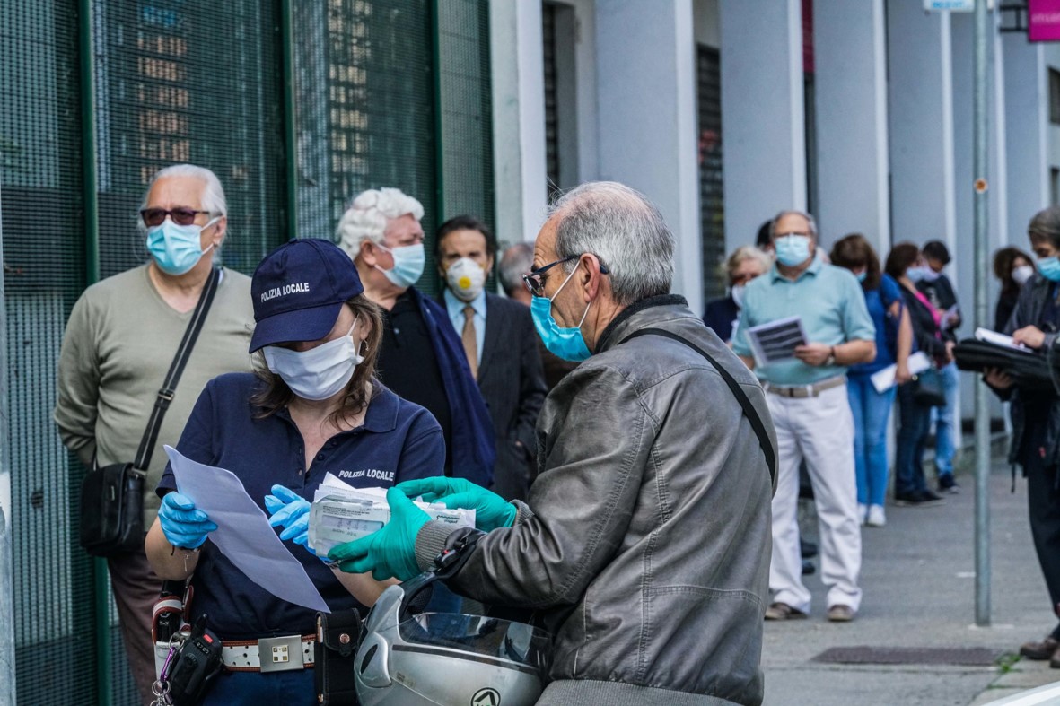 Persone in fila all'esterno di un comando di Polizia Municipale a Torino per pagare multe e permessi