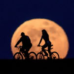 Una coppia di ciclisti pedala con la "Luna dei fiori" sullo sfondo a Salgotarjan, in Ungheria