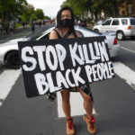 Una ragazza espone un cartello: "Smettetela di uccidere le persone di colore"