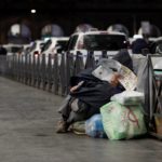 Un senzatetto davanti all'uscita della stazione