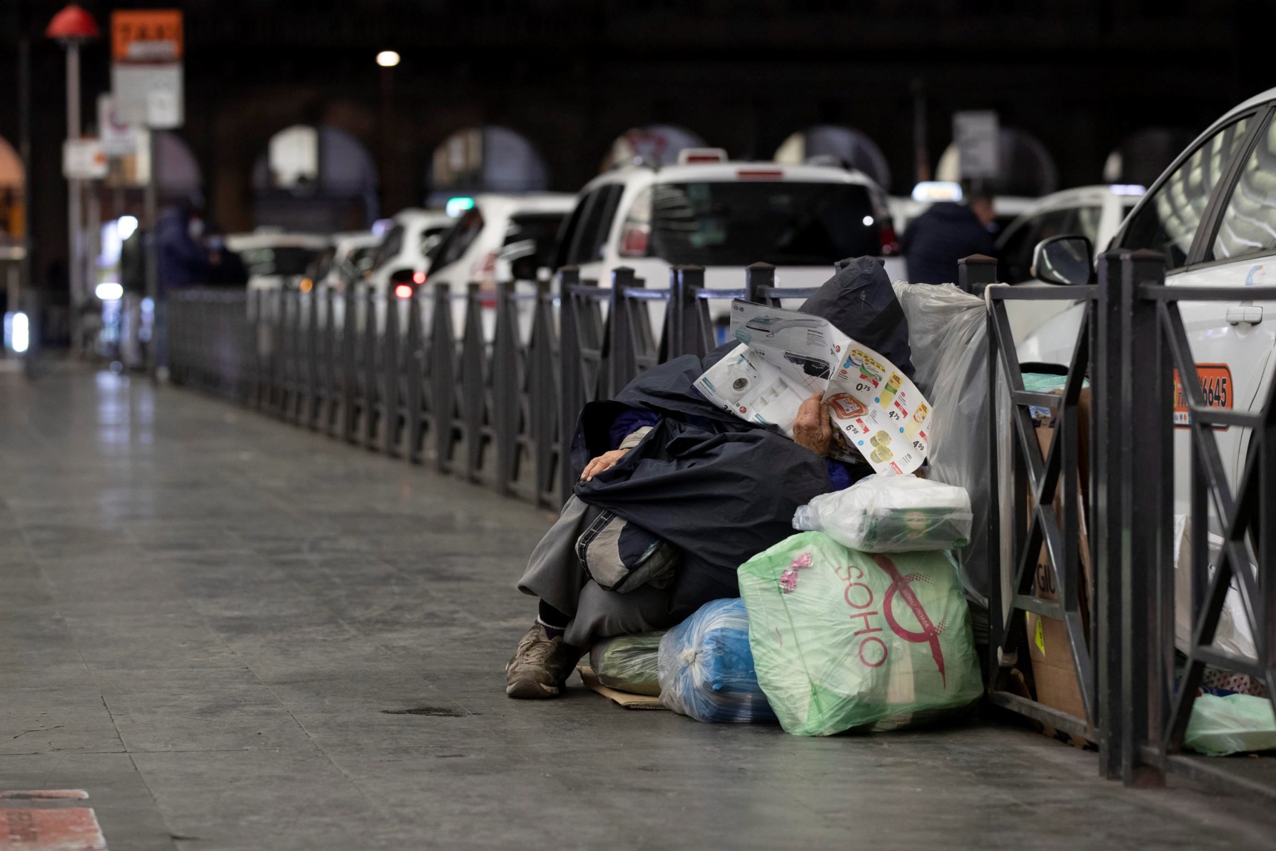 Un senzatetto davanti all'uscita della stazione