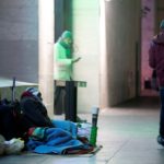 Un senzatetto prova a dormire appoggiandosi su una valigia